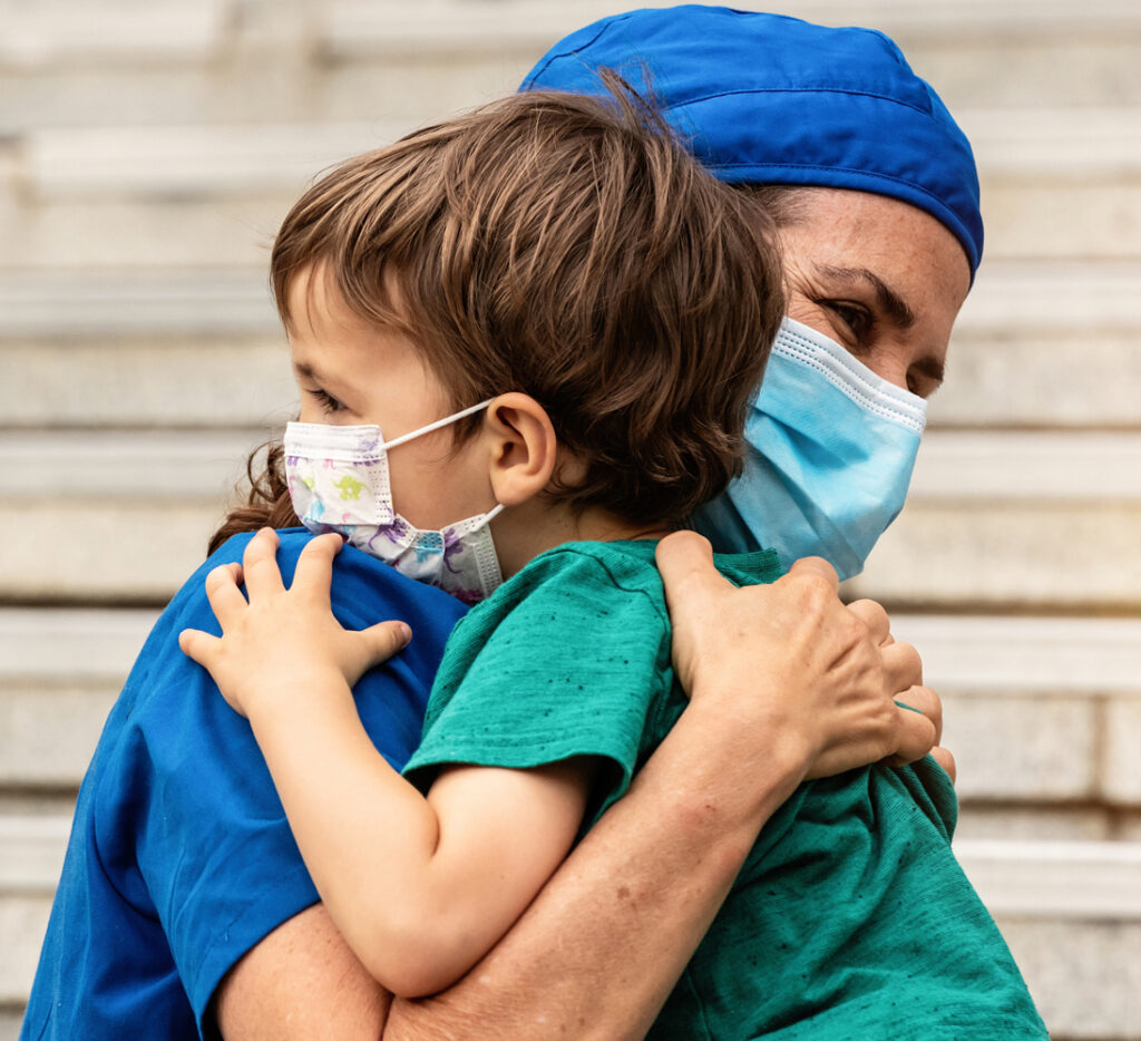 young child hugging a healthcare worker in masks